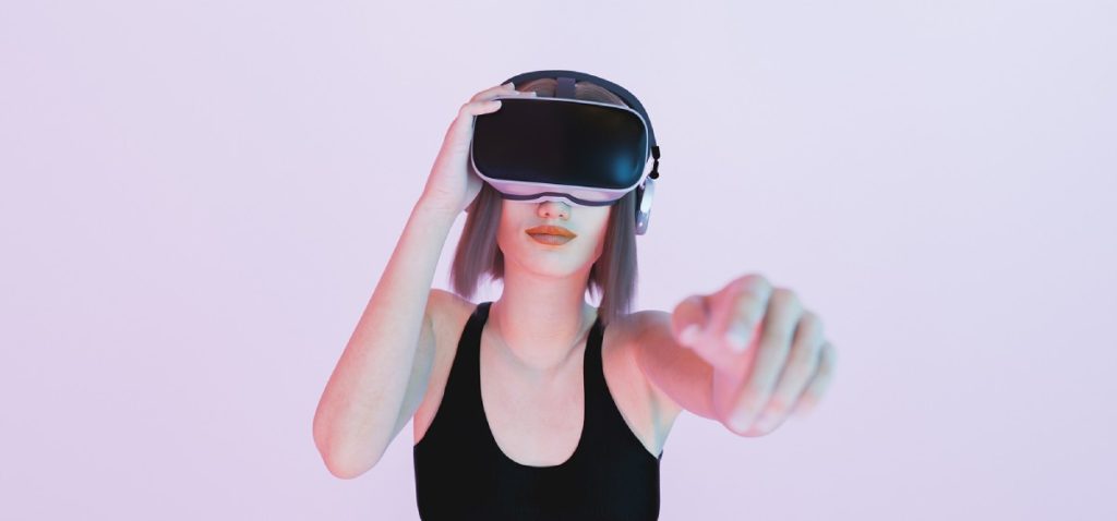 girl playing with virtual reality goggles pointing with her hand out of focus to the camera with blue and pink lights